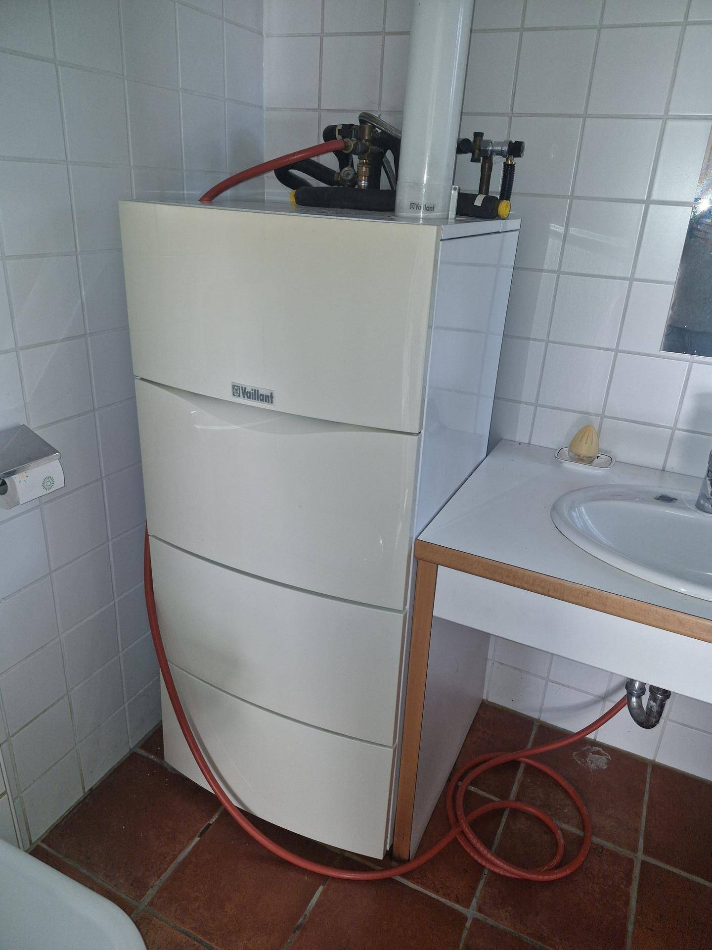 Heizungsanlage von Vaillant neben einem Waschbecken in einem gefliesten Raum.
