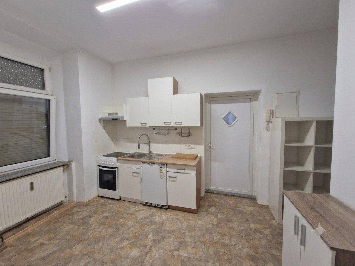 Funktionale Einbauküche mit weißen Schränken, Herd und Fenster.