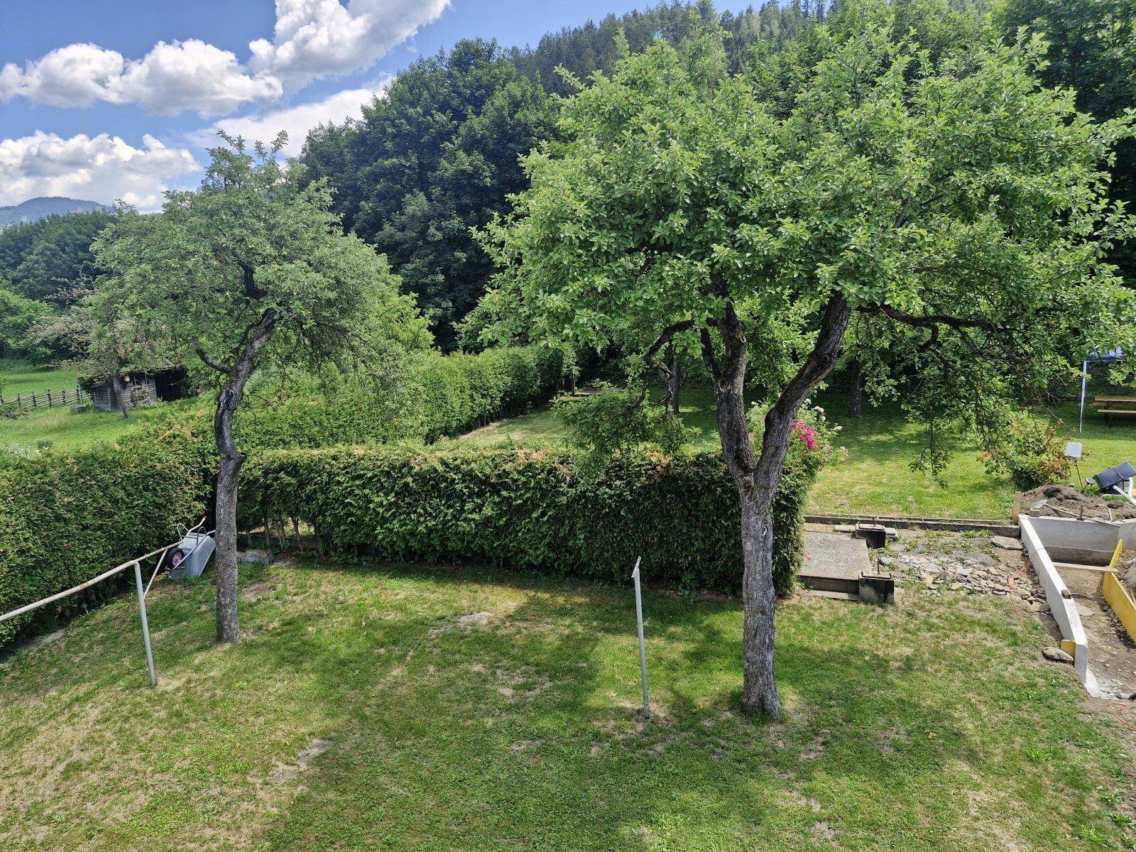 Großer Garten mit Obstbäumen, Hecken und Blick auf die umliegende Natur und Hügel.