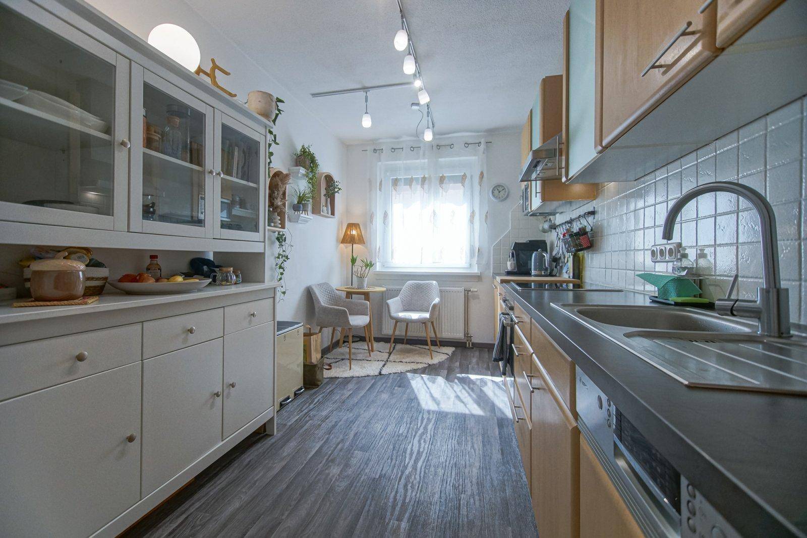 Geräumige Küche mit Essbereich, hellen Holzschränken und viel Tageslicht durch das Fenster.