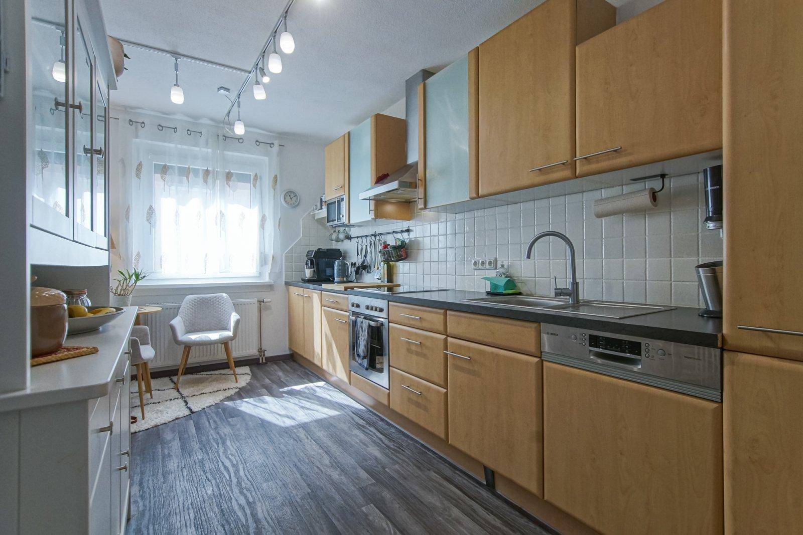 Funktionale Einbauküche mit hellen Holzfronten, modernen Geräten und Laminatboden.