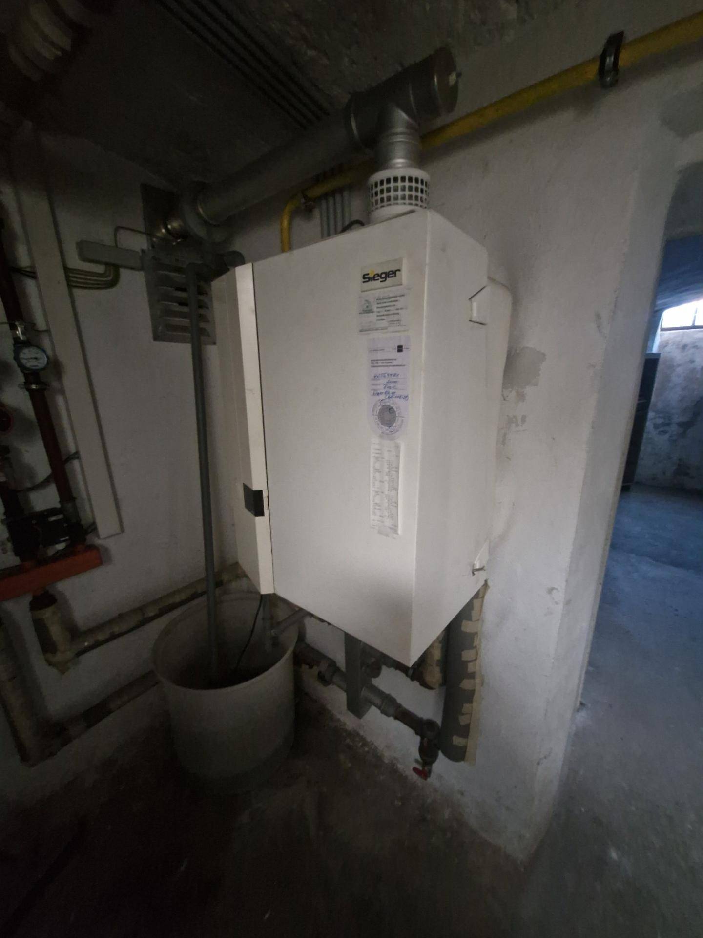 Technikraum im Keller mit Heizungsanlage und sichtbaren Rohrleitungen, funktional und praktisch.