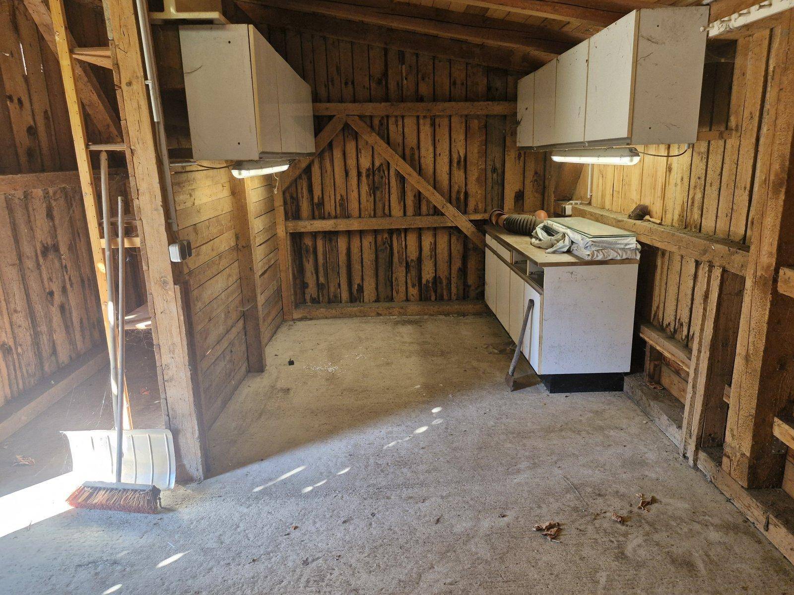 Rustikale Garage oder Werkstatt mit Holzwänden, Betonboden und einfachen Schränken.