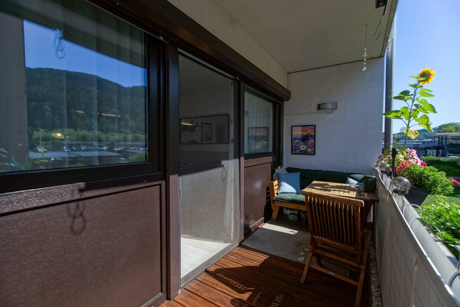 Gemütlicher Balkon mit Holzfußboden, Sitzgelegenheiten und weitem Blick auf die grünen Hügel.