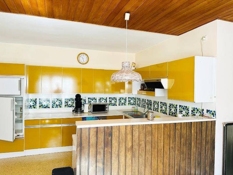 Helle Küche mit gelben Schränken, Holztheke und traditionellen Fliesen.