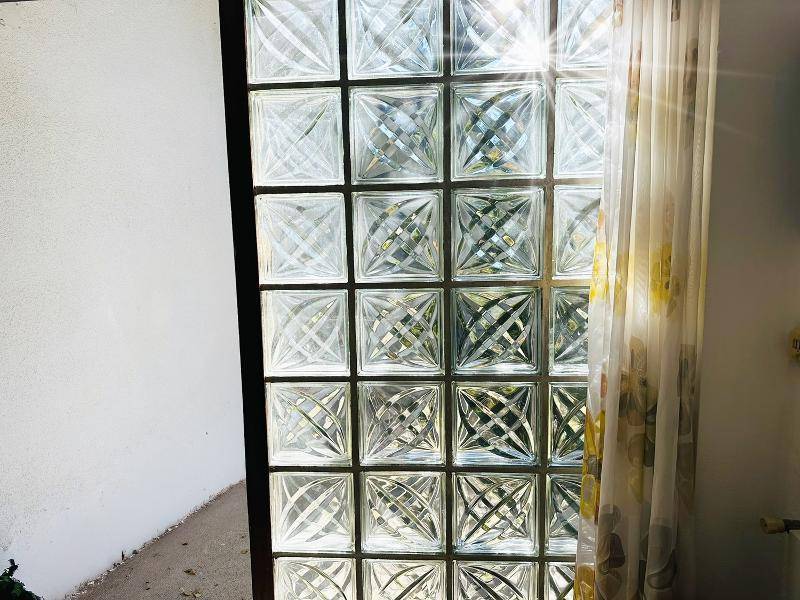 Glasbausteinfenster lässt Sonnenlicht in den Raum, mit einem Vorhang an der Seite.