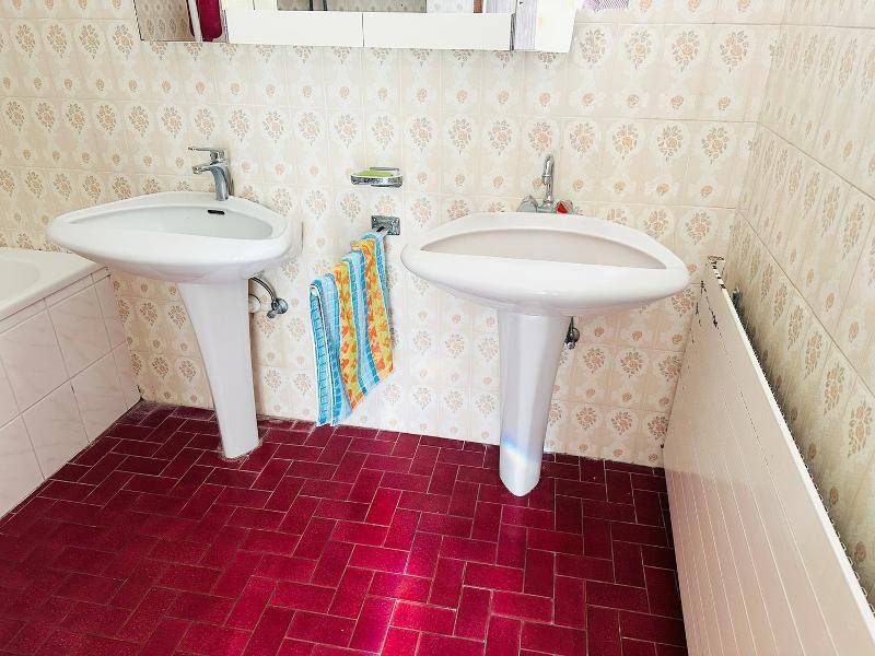 Badezimmer mit zwei Waschbecken und roten Fliesen auf dem Boden, im traditionellen Stil.