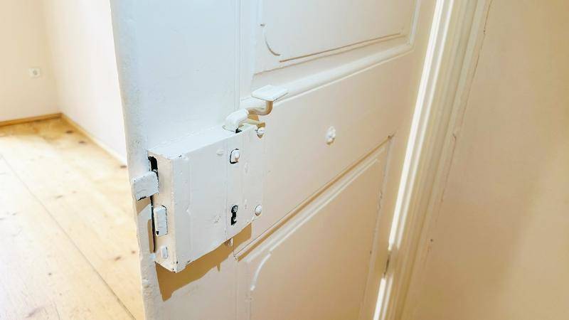 Detailansicht einer alten, weiß gestrichenen Holztür mit traditionellem Riegelverschluss.