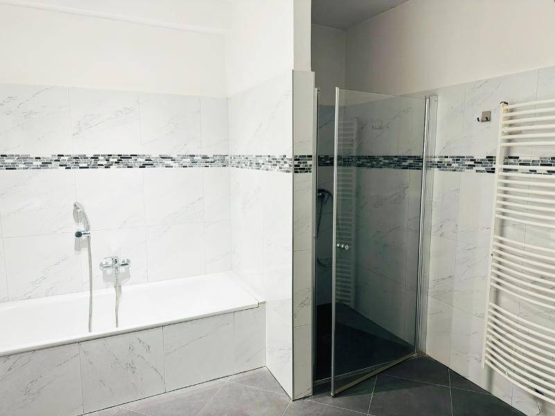 Modernes Badezimmer mit Badewanne, Duschkabine und beheiztem Handtuchhalter.