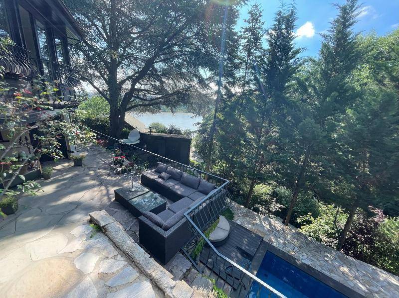 Weitläufige Terrasse mit Lounge-Möbeln und Pool, bietet einen malerischen Blick auf den See.