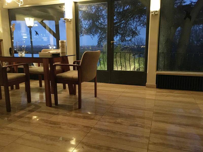 Essbereich mit Holztisch und Stühlen, großen Fenstern und Blick auf die nächtliche Landschaft.