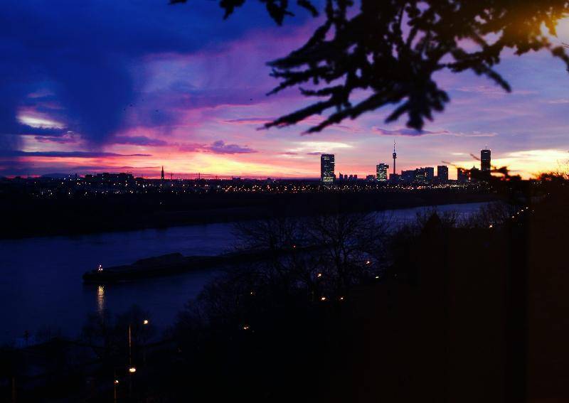 Beeindruckende Stadtansicht bei Dämmerung mit beleuchteter Skyline und Fluss.