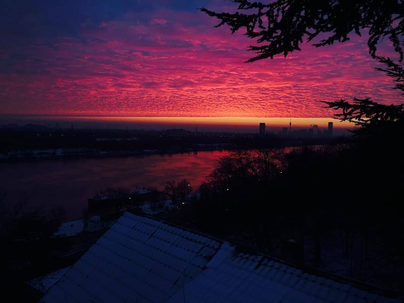 Spektakulärer Sonnenuntergang über der Stadt und dem Fluss, mit leuchtendem Himmel.