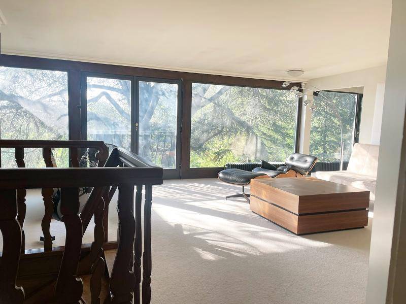 Lichtdurchflutetes Wohnzimmer mit großen Fenstern, die einen weiten Blick in die Natur bieten.
