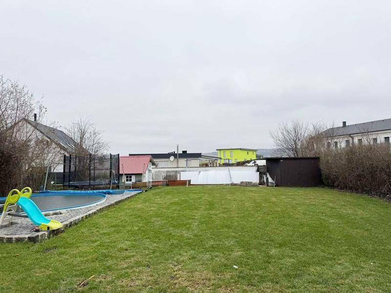 Großer Garten mit Rasenfläche, Aufstellpool, Trampolin und einem Geräteschuppen.