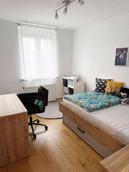 Kinderzimmer mit Einzelbett, Schreibtisch und einem Fenster, das viel Licht spendet.
