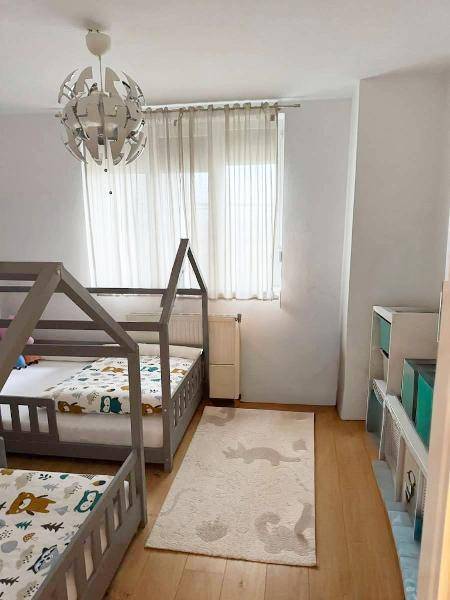 Helles Kinderzimmer mit zwei einzigartigen Hausbetten und einem großen Fenster.