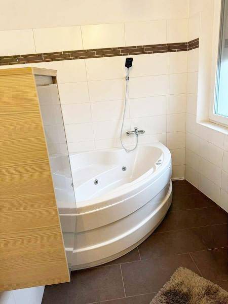 Eckbadewanne mit Duschfunktion in einem gefliesten Badezimmer, ideal zum Entspannen.