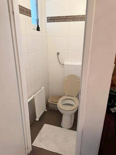 Kleines WC mit Toilette und einem Fenster für Belüftung und Tageslicht.