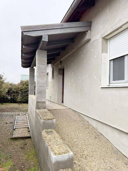 Seitenansicht des Hauses mit überdachtem Eingang und einer barrierefreien Rampe.