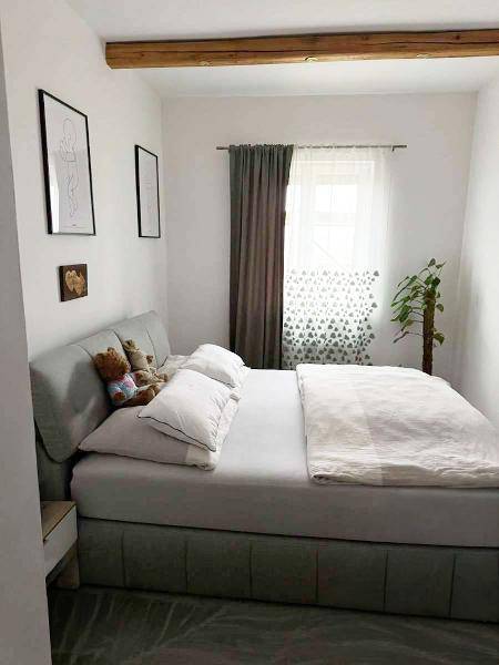 Gemütliches Schlafzimmer mit Doppelbett, Fenster und einem sichtbaren Holzbalken an der Decke.