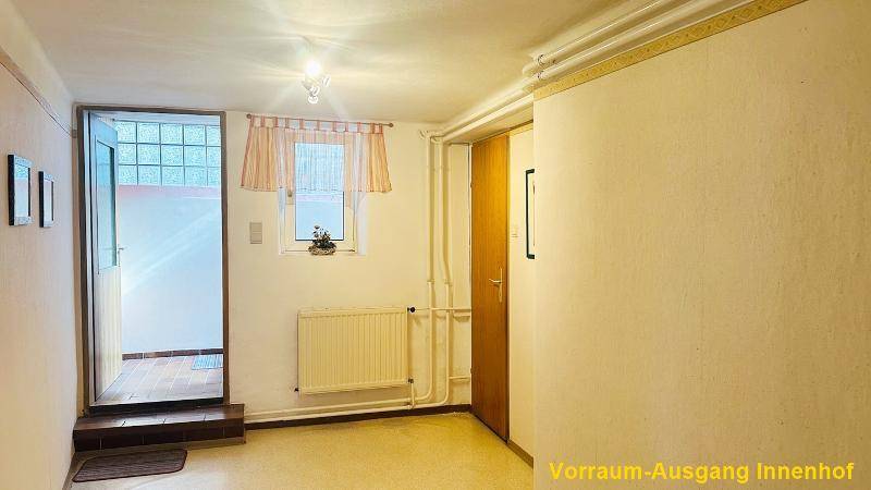 Eingangsbereich mit Zugang zum Innenhof, ausgestattet mit einem Fenster und Heizkörper.