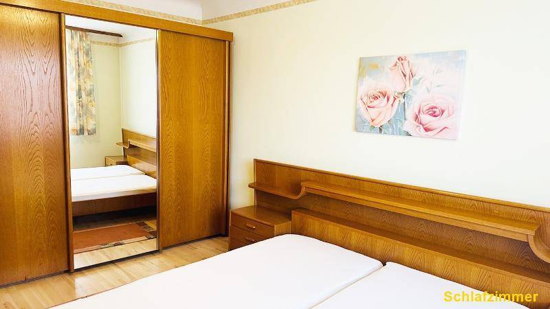 Gemütliches Schlafzimmer mit großem Spiegelschrank, Doppelbett und floraler Wanddekoration.