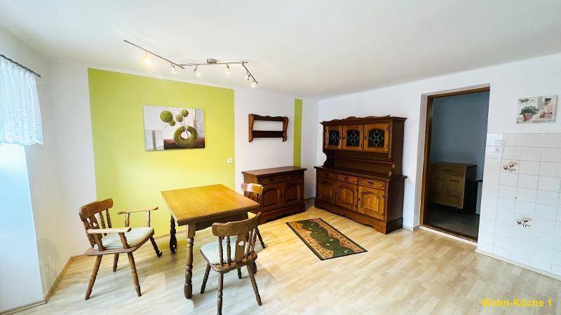 Geräumiger Wohn-Essbereich mit traditionellen Holzmöbeln, hellem Laminatboden und grüner Akzentwand.