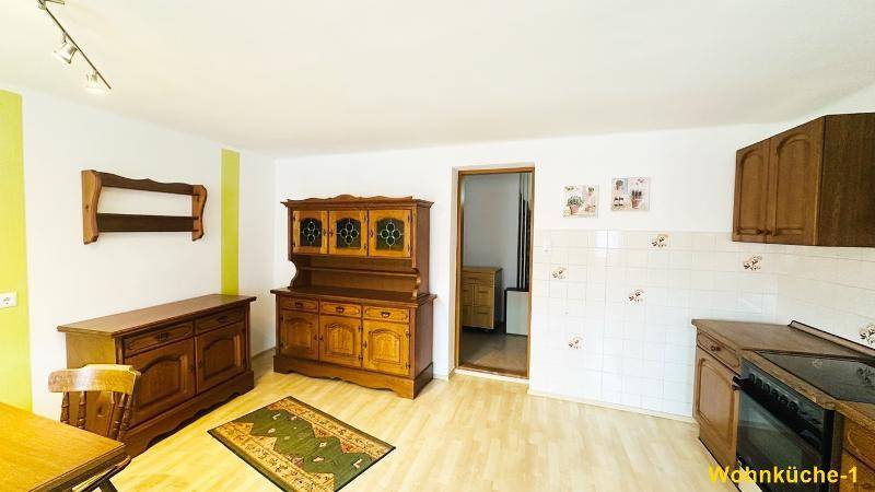 Traditionelle Wohnküche mit Holzschränken, Esstisch und gefliestem Bereich, bereit zur Nutzung.