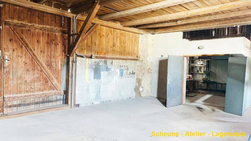 Geräumige Scheune oder Lagerraum mit hohen Holztoren und sichtbaren Deckenbalken.