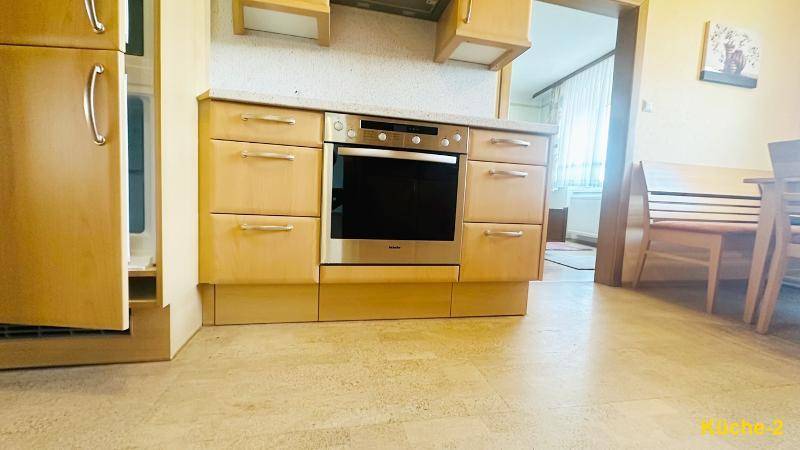 Moderne Einbauküche mit hellem Holzdekor, integriertem Backofen und funktionaler Arbeitsplatte.