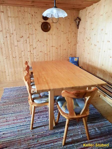 Gemütliches Kellerstüberl mit großem Holztisch, Stühlen und warmer Holzvertäfelung.