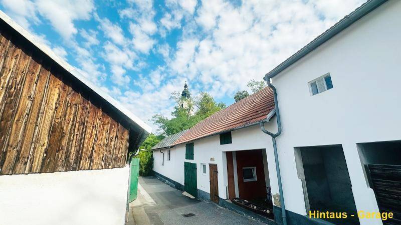 Hinterhausansicht mit schmaler Gasse und Zugang zu einer Garage, umgeben von weiteren Gebäuden.