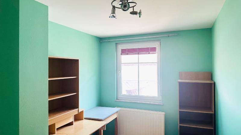 Zimmer mit grünen Wänden, Holzfußboden und Deckenleuchte.