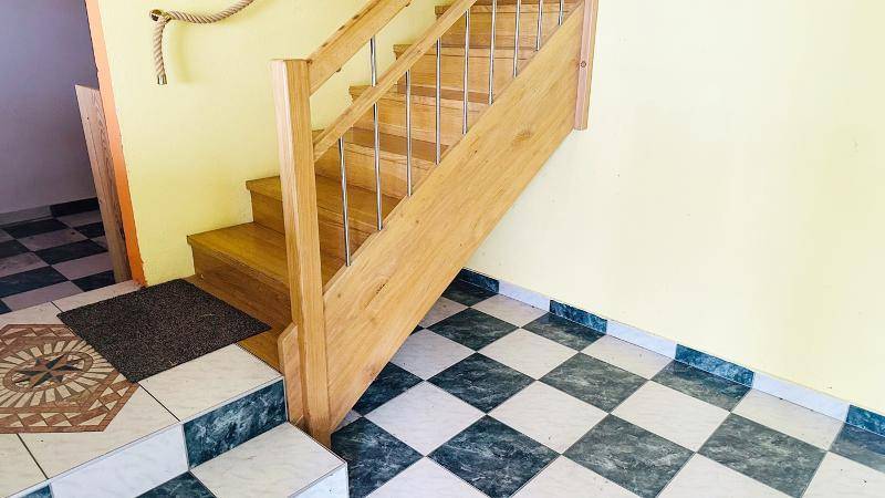 Heller Flur mit Holztreppe und auffälligem schwarz-weißem Fliesenboden.
