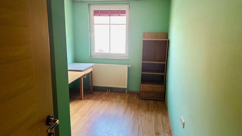 Helles Zimmer mit grünen Wänden, Holzfußboden und einem Fenster.
