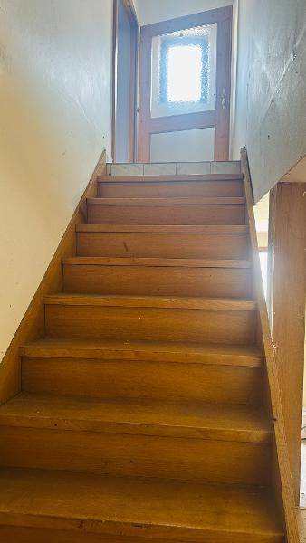 Holztreppe mit Holztür am oberen Ende, die nach oben führt.