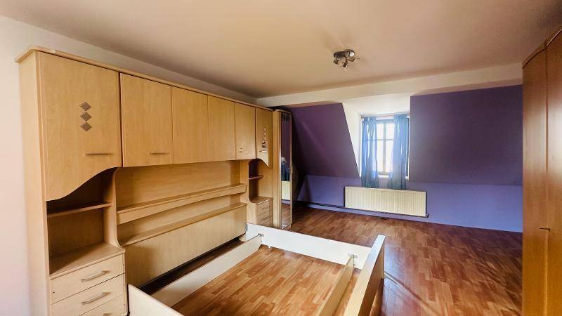 Schlafzimmer im Dachgeschoss mit lila Wänden, Holzfußboden und Einbauschrank.