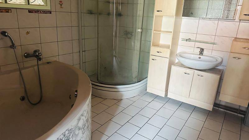 Badezimmer mit Eckbadewanne, Duschkabine, Waschbecken und hellen Fliesen.