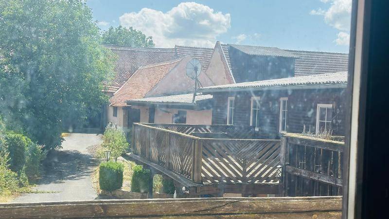 Blick aus dem Fenster auf benachbarte Gebäude und eine Holzterrasse.