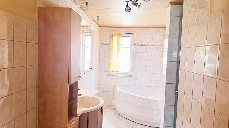 Badezimmer mit Eckbadewanne, Duschkabine und Holzdecke.