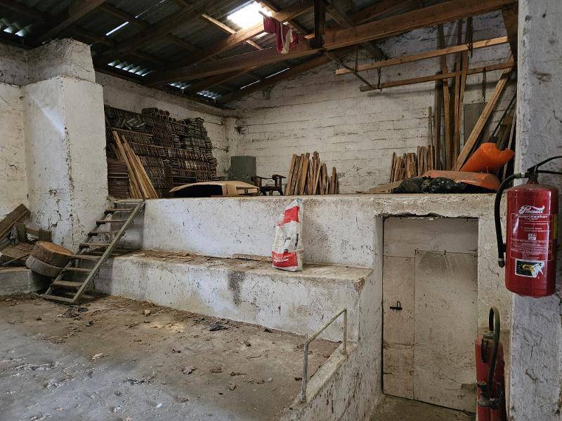 Großer Lagerraum mit hohen Decken, sichtbaren Holzbalken und einem Feuerlöscher an der Wand.