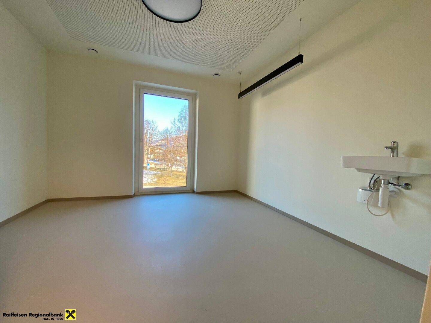 Heller Raum mit einem Waschbecken und einem großen Fenster, das einen weiten Blick auf die Natur ermöglicht.