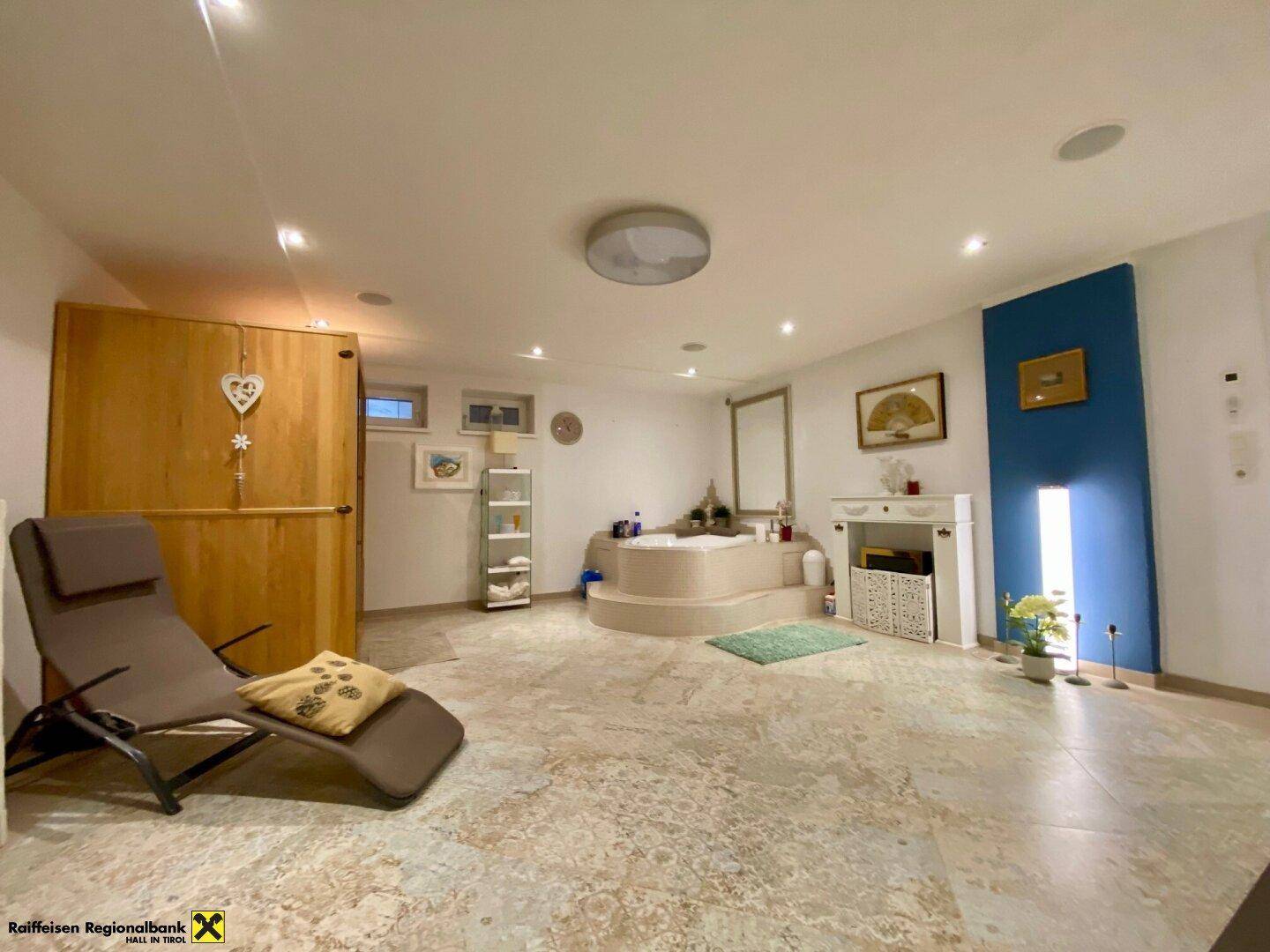 Geräumiger Wellnessbereich mit Whirlpool, Sauna und Entspannungsliege.