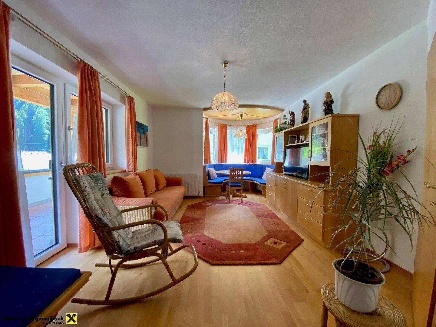 Helles Wohnzimmer mit Holzboden, bequemer Couch und Zugang zu einem Außenbereich.