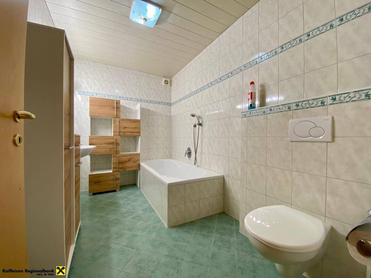 Helles Badezimmer mit Badewanne, WC und Waschbecken in schlichter Ausführung.