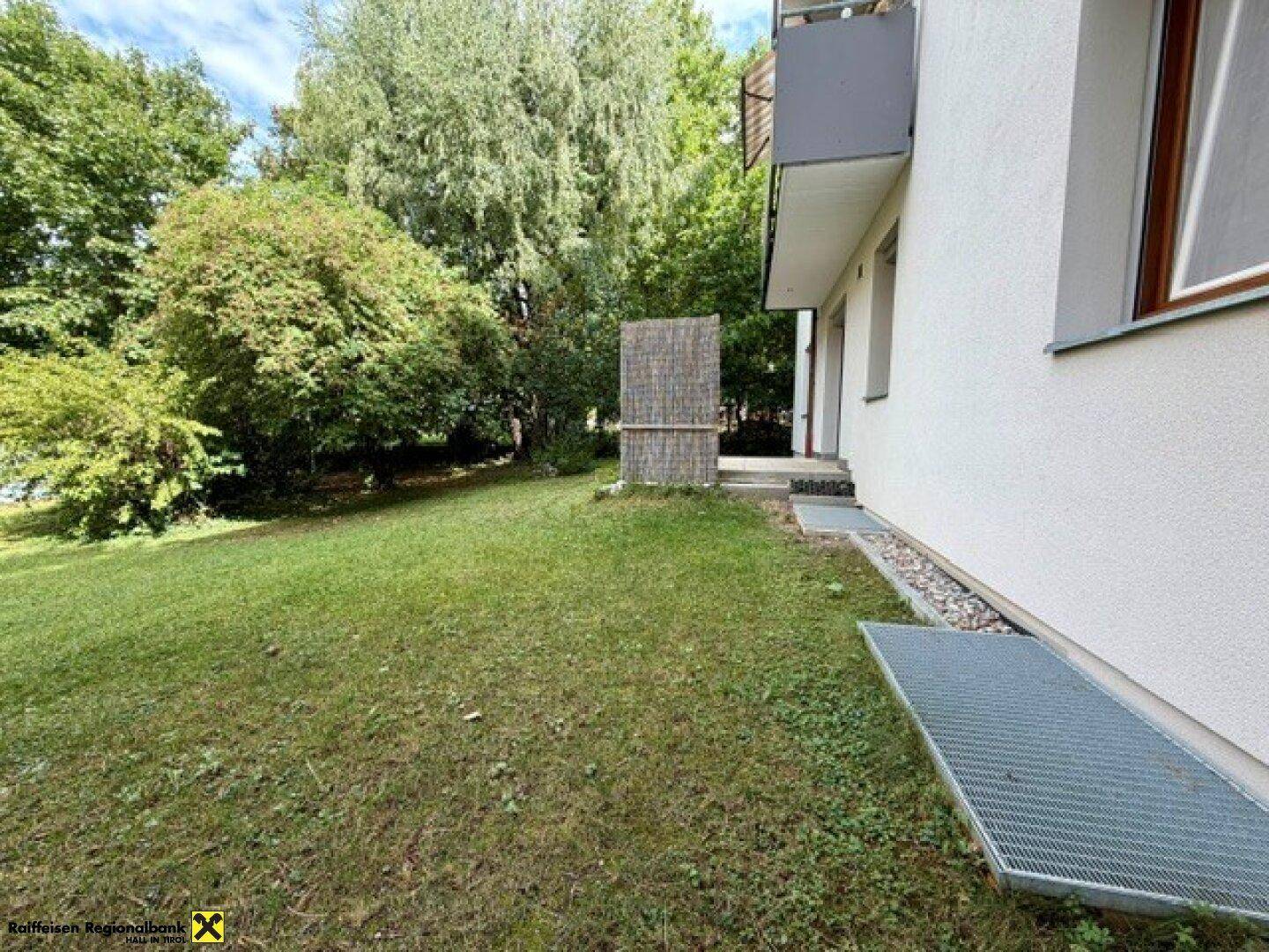 Seitliche Ansicht des Gebäudes mit einem weitläufigen Rasen und Bäumen im Hintergrund.