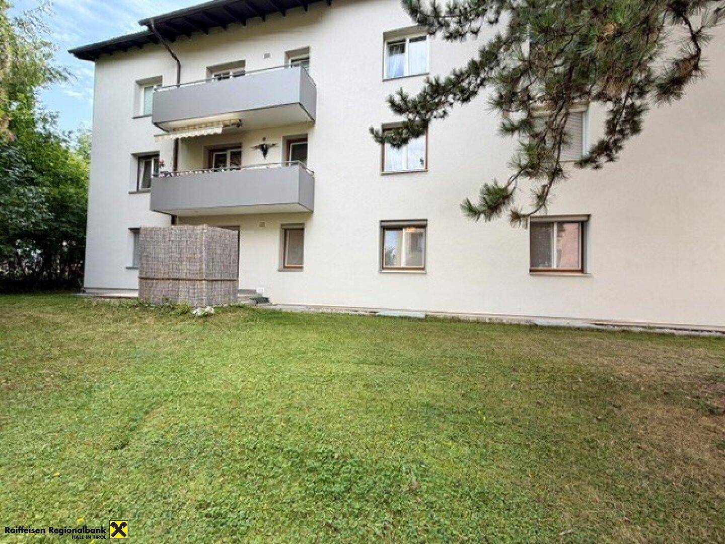 Vorderansicht des Mehrfamilienhauses mit Balkonen und einem gepflegten Rasenbereich.