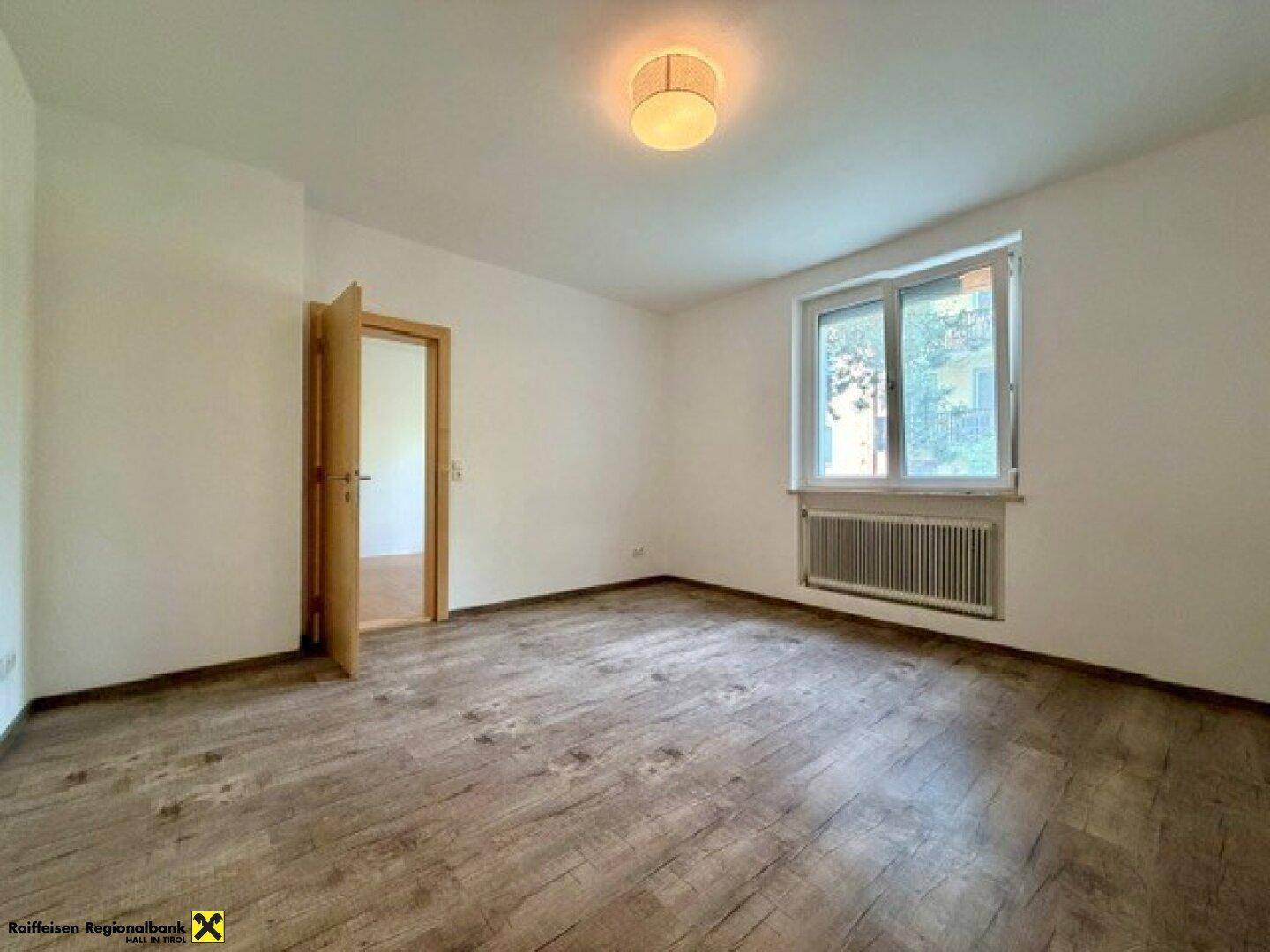 Helles Schlafzimmer mit Laminatboden und großem Fenster, bereit zur individuellen Gestaltung.