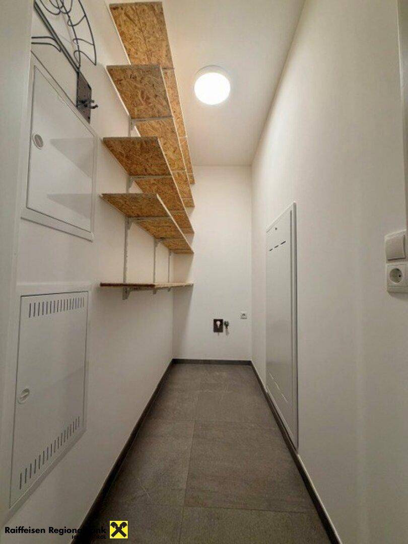 Funktionaler Hauswirtschaftsraum mit praktischen Regalen und Fliesenboden für zusätzlichen Stauraum.